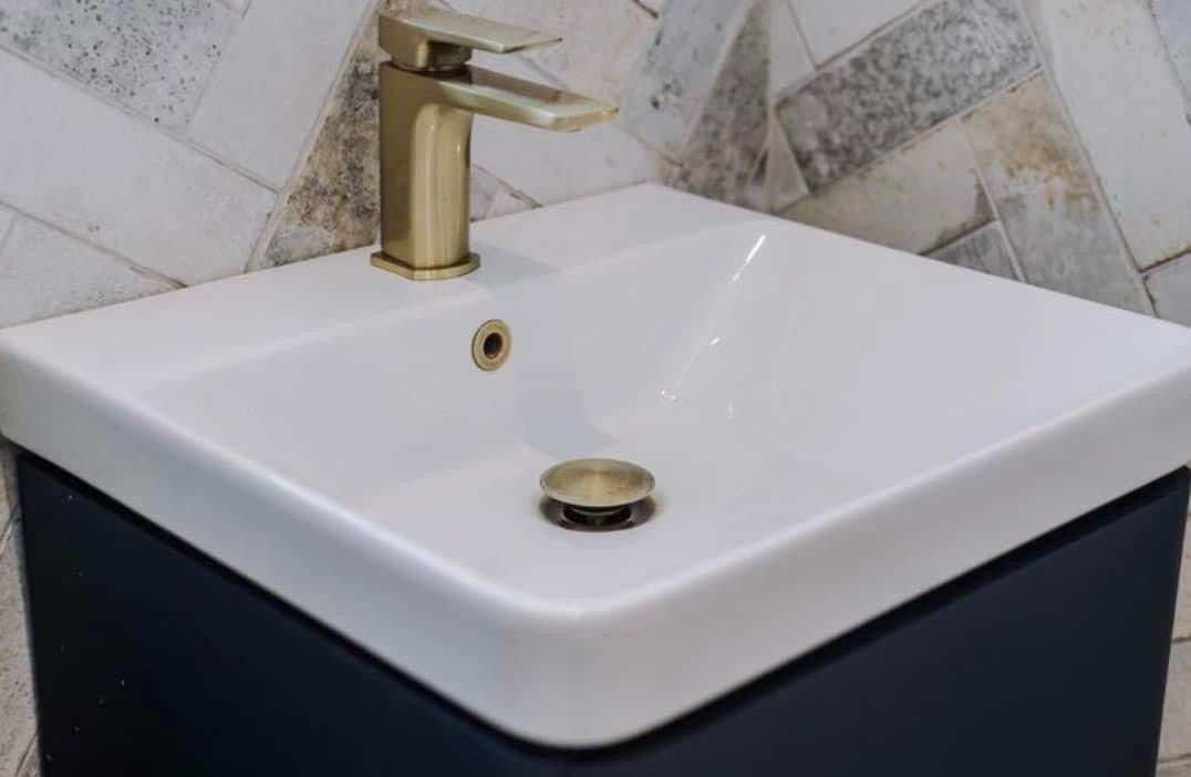Square basin with a brushed brass tap on a navy vanity