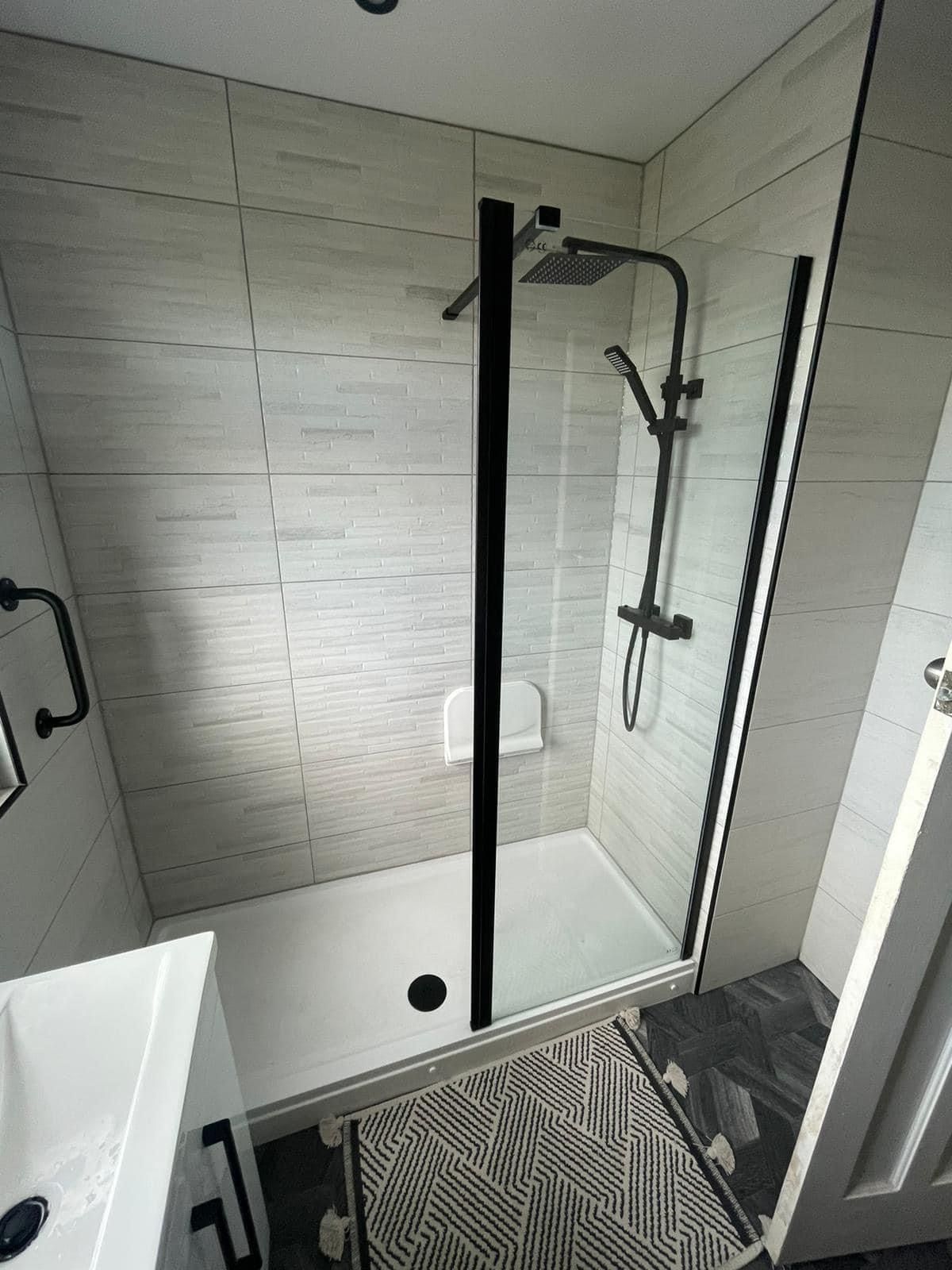 Walk-in shower with a black-framed glass screen and patterned floor tiles