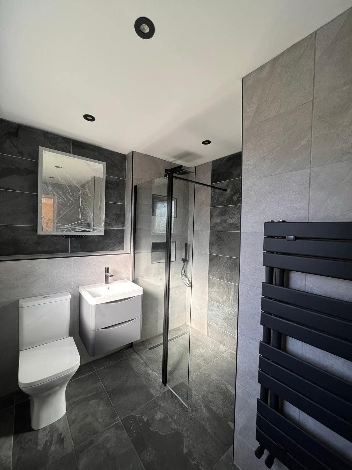 Shower room with dark tiles and a black towel radiator